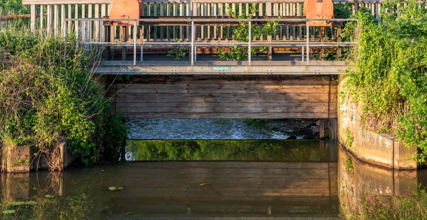 A weir on the Heubach at Dülmen: a timber sill across the channel with water running under the walkway